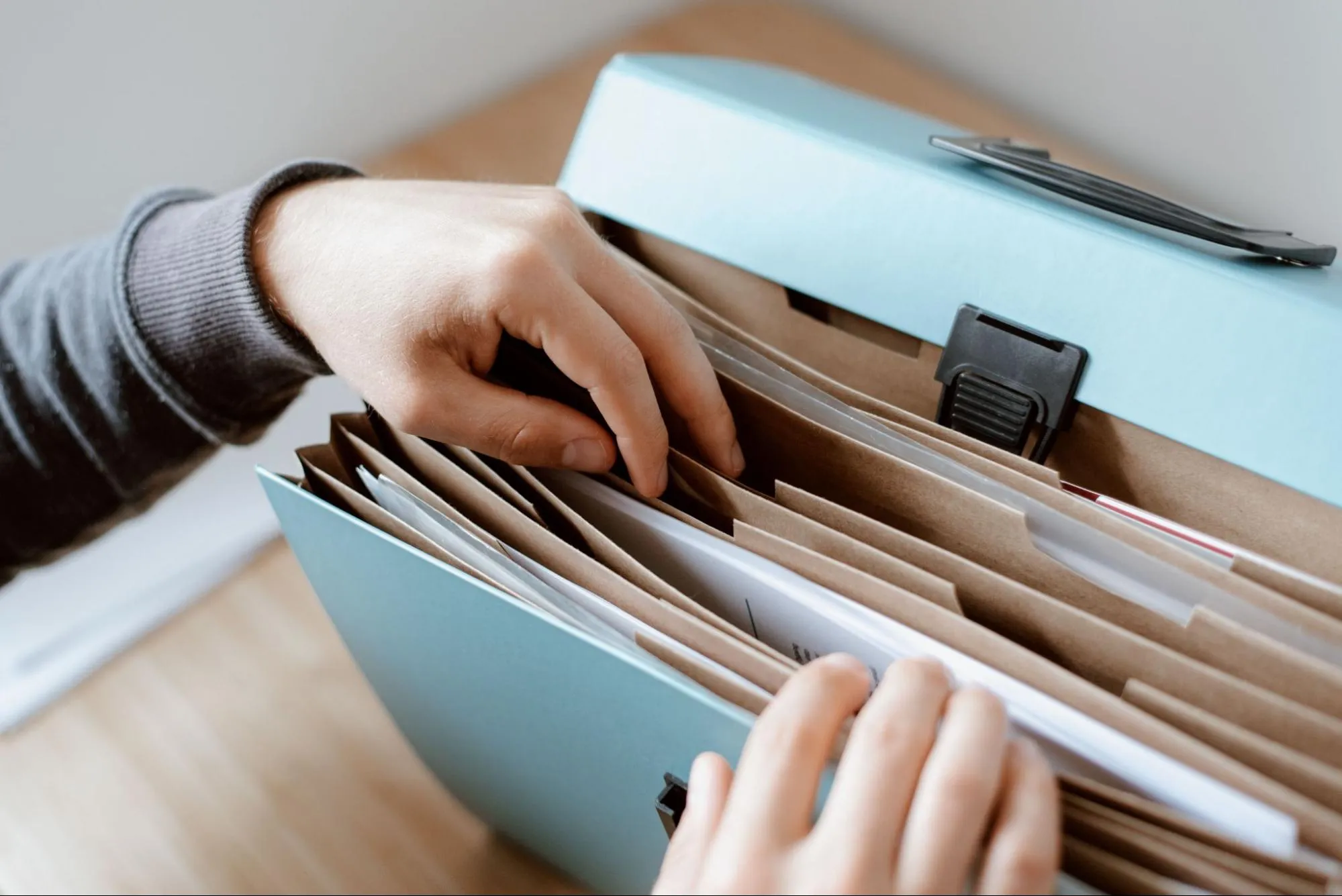 Hands searching through an expanding file folder, representing the national VAT databases that VIES queries