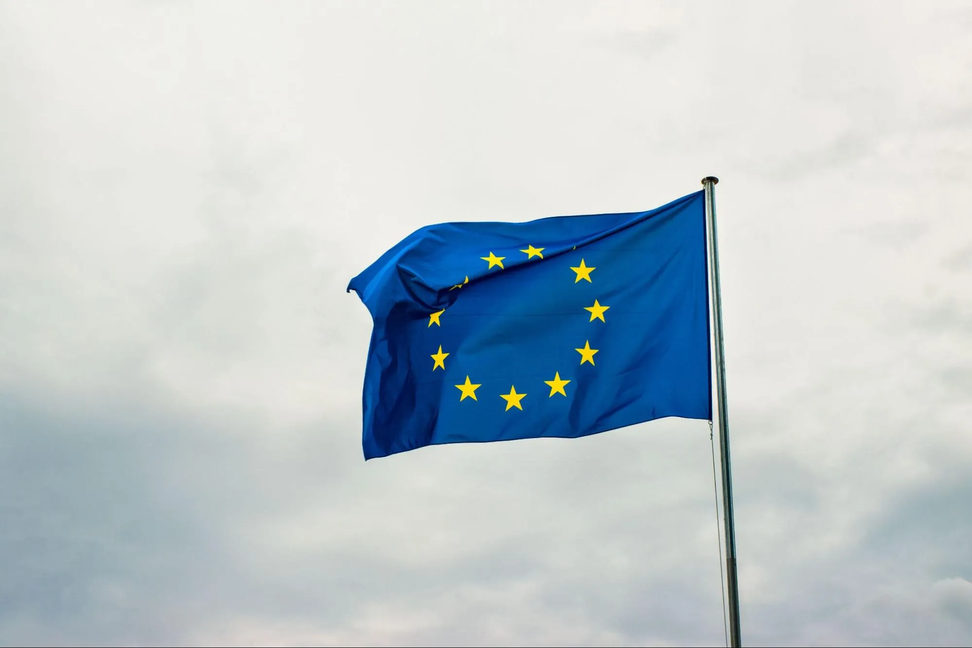 The flag of the European Union flying against an overcast sky, representing the shared EU legal framework