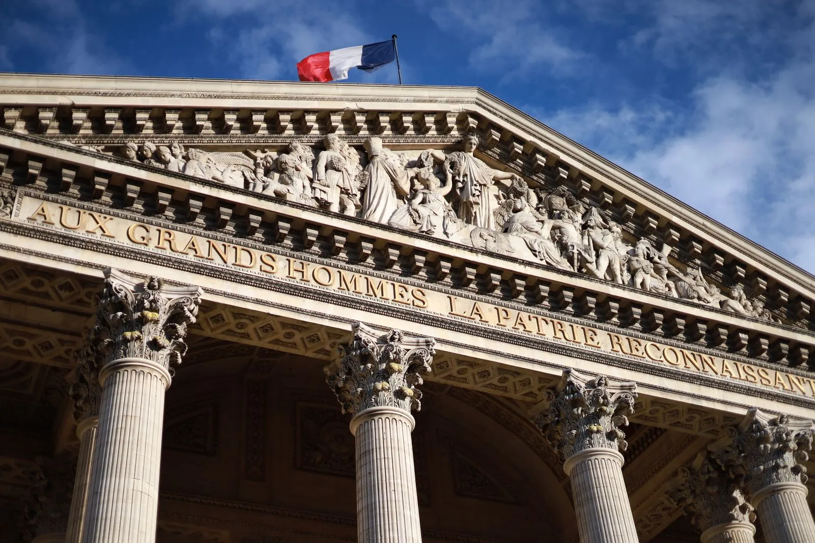パリのパンテオンの破風の上に掲げられたフランス国旗。「Aux grands hommes la patrie reconnaissante」の銘が刻まれている