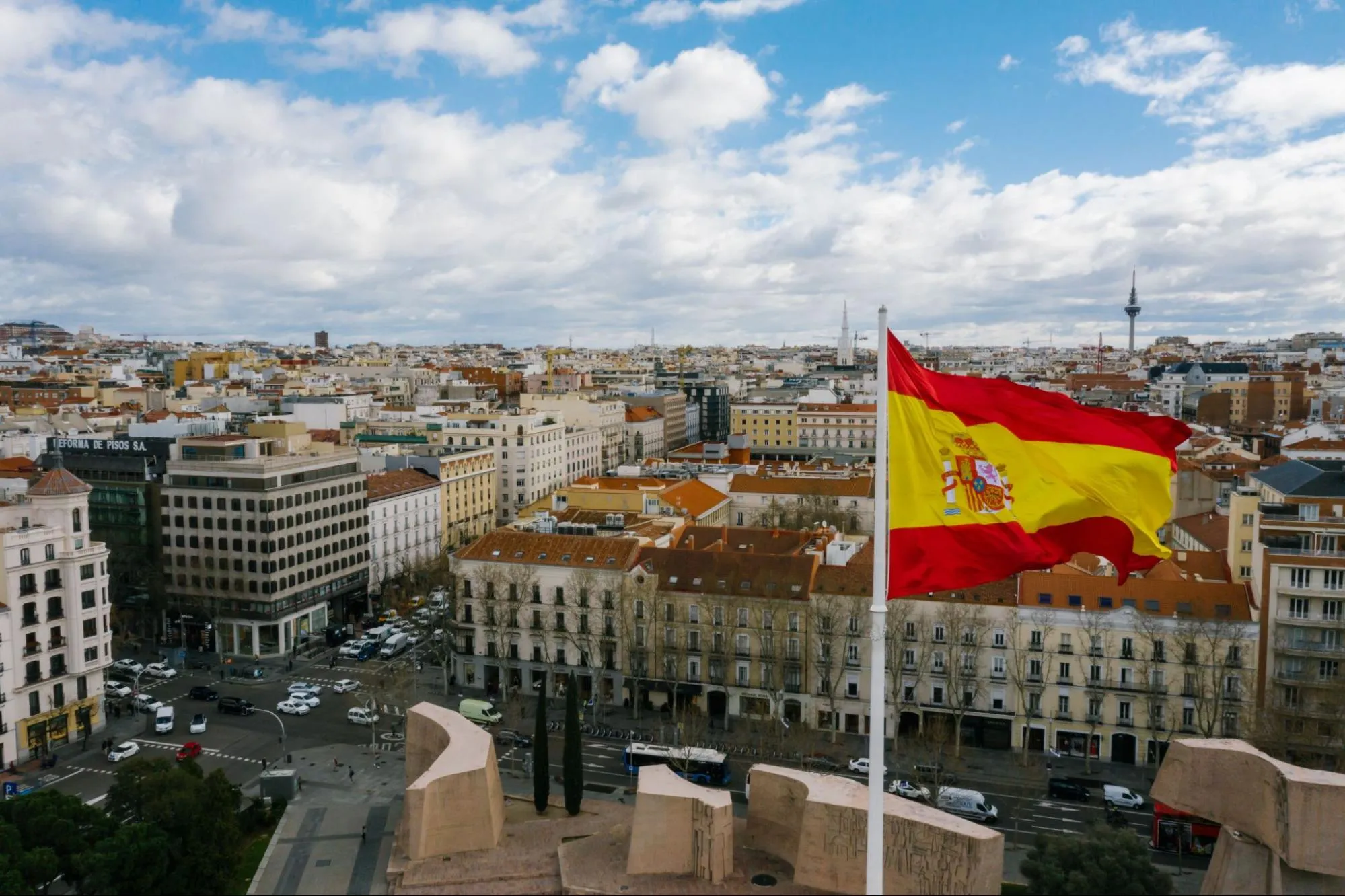 The Spanish flag flying above the rooftops of central Madrid seen from above on a cloudy day